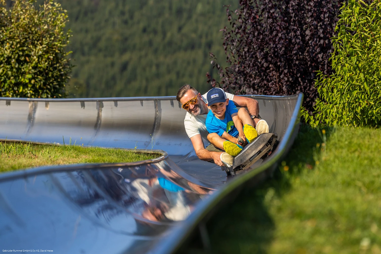 Mann und Junge auf der Sommerrodelbahn